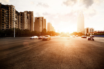 sun skyline and traffic on urban road through city buildings