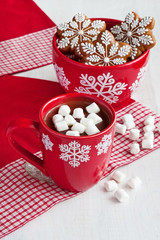 Red mugs with hot chocolate and marshmallows and gingerbread cookies 