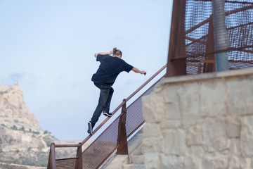 Back view of young man jumping on railing