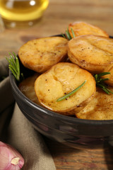 Delicious baked potato with rosemary in bowl on table close up