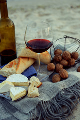 Beautiful romantic composition of red wine, bread and nuts on sandy beach