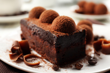 Slice of chocolate cake with a truffle on plate closeup