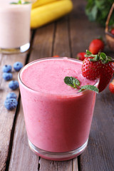 Glasses of fresh cold smoothie with fruit and berries, on wooden background