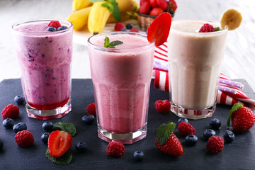 Milkshakes at cutting board with berries on light background