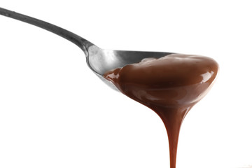 Melted milk chocolate pouring from a spoon, isolated on white