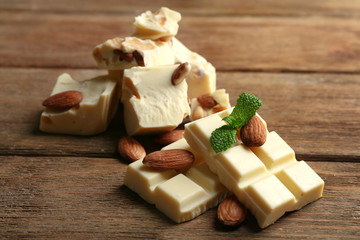 White chocolate pieces with nuts on color wooden background