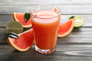 Glass of grapefruit juice and fresh fruits on wooden background