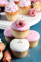 Tasty cupcakes on stand, on color wooden background