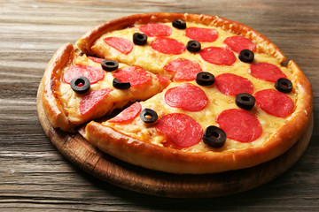 Hot tasty pizza with salami and olives on wooden background