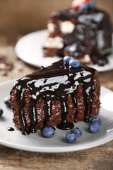 Chocolate cake with chocolate cream and fresh blueberries on plate, on wooden background