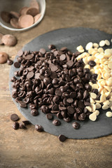 Chocolate morsels on board, on wooden background