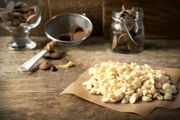 Chocolate morsels on board, on wooden background