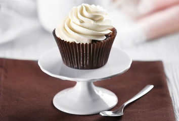 Delicious chocolate cupcake with cream on served table, close up