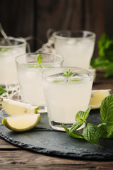 Fresh cocktail with lemon, ice and mint on the vintage table