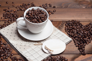 White cup and coffee grains on a wooden surface