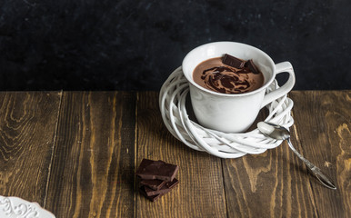 Cup of hot chocolate on vintage wooden background and chocolate slice