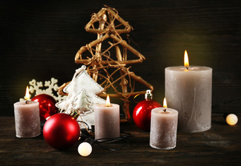 Burning candles with Christmas accessories on wooden background