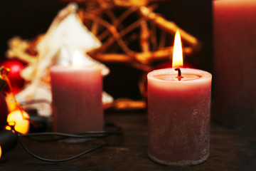 Burning candles with Christmas accessories on wooden background