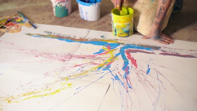Close-up of artist splattering paint to create an abstract artwork