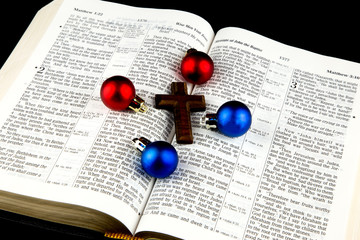 Christmas Baubles and Cross on Bible on Black Background