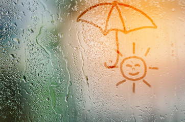 draw sun holding umbella on natural water drops glass window bac