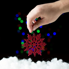 Red snowflake in the hand  on the black background with colorful