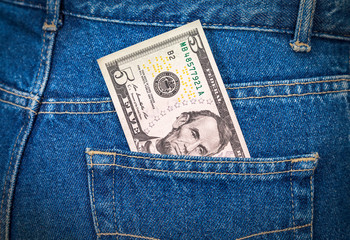 Five dollars bill sticking out of the blue jeans pocket