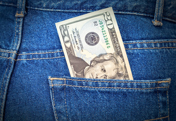 Banknote of twenty dollars sticking out of the blue jeans pocket