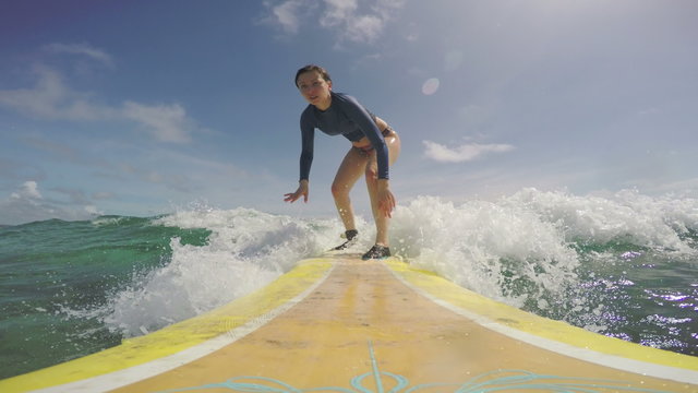 Amateur surfer girl riding a wave on a longboard, soo happy she succeeded
