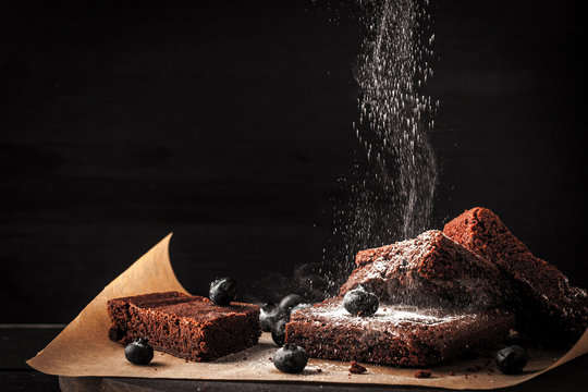 Sprinkling chocolate brownie with icing sugar and blueberry