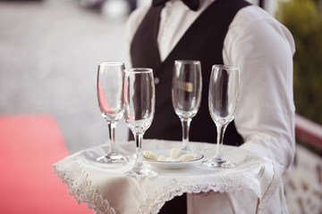 Waiter with glasses for champagne on tray