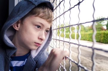 Sad boy closeup behind bars