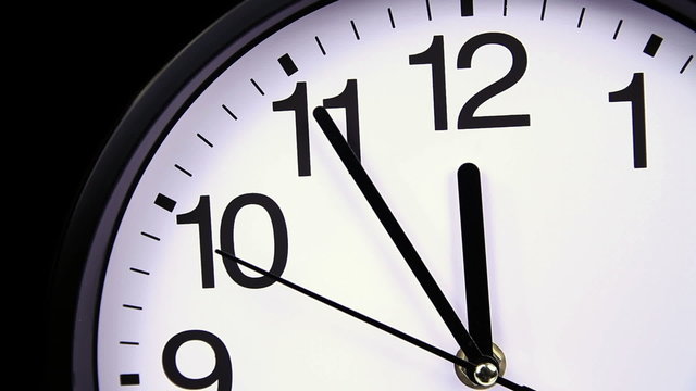 Wall clock on a black background 23:55 close-up