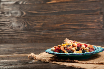Dried fruits. Hazelnuts, almonds, cashews, apricots, cherries, walnuts, raisins. Background - Turkish plate and burlap. Vintage.