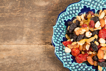 Dried fruits. Hazelnuts, almonds, cashews, apricots, cherries, walnuts, raisins. Background - Turkish plate and burlap. Vintage.