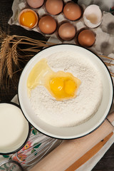 ingredients for homemade bread on vintage wooden background and towel with embroidered ears of wheat, milk, eggs, flour, dough, bread