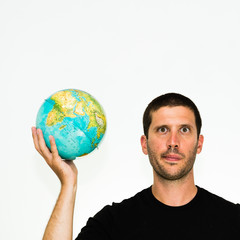 close-up of disheartened caucasian man holding a world globe in his hand with funny expression - conceptual image isolated on white background with copyspace