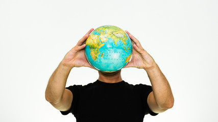 close-up of smiling caucasian man holding a world globe in front of his head - conceptual image...