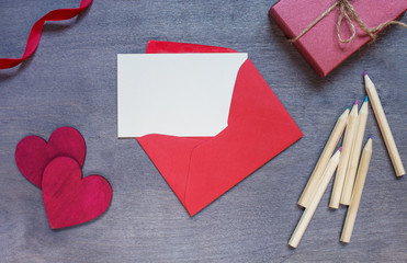 Red envelope with a gift and two wooden hearts.