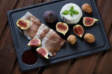 Basalt plate with ricotta cheese, ripe figs, ham and walnuts