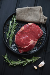 Frying pan with raw fresh seasoned ribeye beefsteak, top view