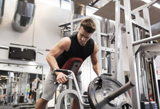 young man exercising on t-bar row machine in gym