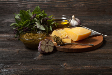 Green basil pesto - italian recipe ingredients on black chalkboard from above. Parmesan cheese, basil leaves, pine nuts, olive oil, garlic