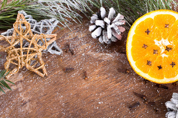 Christmas backgrounf with orange, cloves, stars and fir branches on wooden background