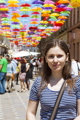 Tourist young woman on a street decorated with colored and open umbrellas
