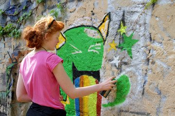 Jungendliche sprüht Graffiti an Fassade - 98181999