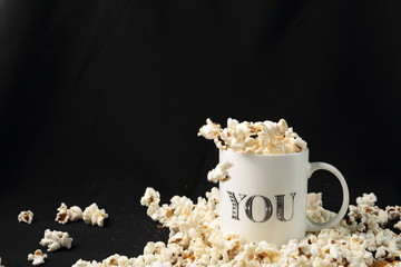 White jar with popcorn on black background
