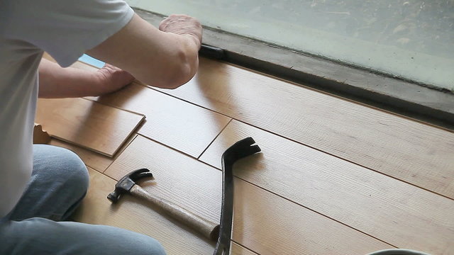 Man uses nail puller on laminate floor 