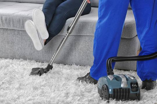 Cleaning concept - man cleaning the room with carpet sweeper, close up