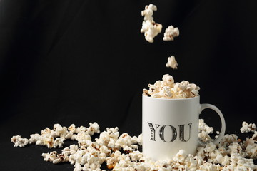 White jar with popcorn on black background
